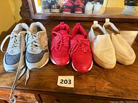 Three pairs of sneakers side by side on wooden surface