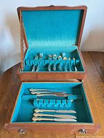 Open chest showing upper and lower tiers filled with flatware