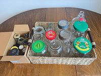 Top view of woven tray holding jars and bottles next to box of small spice jars