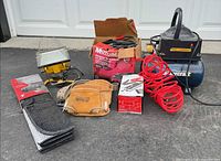 Group shot showing compressor, hose, work light, jump starter box, booster cables, tool pouch, sunshade
