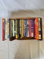 Tray containing roughly 23 paperback books of mixed genres