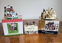 Three collectible pieces shown with original boxes: two skating pond scenes and one Currier & Ives sleigh figurine