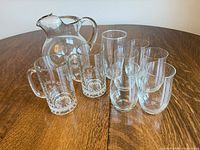Group shot of pitcher, two mugs, pilsner glass and stemless tumblers