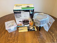 All items group shot: boxed coffee maker, fondue pot in plastic, fork set, storage box