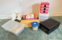 All items in lot arranged together showing storage boxes, baskets, wooden box, tote, plastic drawers, black decorative box and figurines