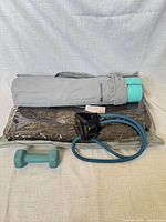 All five items: rolled yoga mat in bag, sealed heating pad, resistance band, dumbbell