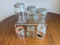All six glass jars and white rack displayed on wooden table