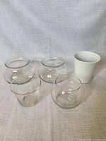 group shot of four clear glass bowls and one white ceramic planter