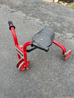 Full view of red Locomotion ride-on showing frame, seat, and three wheels