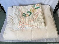 Folded chenille bedspread atop feather/down topper showing overall colors and textures