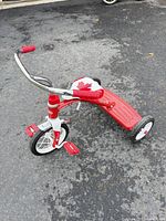 Left side view of red and white Radio Flyer tricycle on pavement