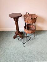 Wood pedestal table, wicker basket stand, metal plant stand grouped