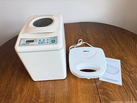 Bread maker and sandwich press side by side on table