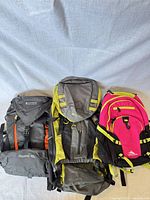 Front view of three backpacks showing brands, colors and sizes