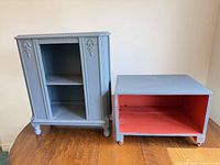 Front view of blue-gray wooden cabinet beside matching storage box showing interiors