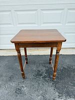 Front angled view of square wood side table showing top surface and two turned legs