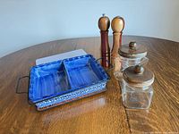 Group shot of baking dish in stand, two jars, two pepper mills