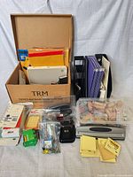 Overall lot showing box of envelopes, desk file organizer with folders, stapler, hole punch, Post-it pads and trays of small fasteners