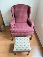 Front view of burgundy wingback chair with cream floral footstool