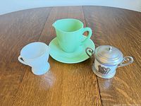 All four items: white milk glass creamer, green jadeite creamer on saucer, silverplate sugar bowl with lid