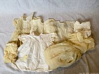 Group shot of all seven vintage infant items laid on fabric backdrop