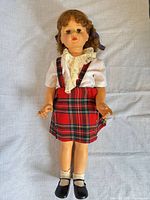 Full view of 36-inch vinyl doll in plaid suspender skirt, white lace blouse, socks, shoes
