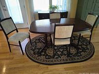 Dining table with four chairs on rug, overall view