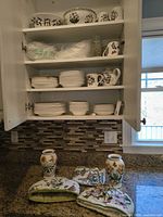 Cabinet interior with dinnerware stacks, vases and textiles displayed on counter