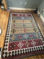 Top view of full multicolor geometric kilim-style area rug on hardwood floor
