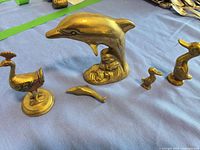 Group shot of all five brass figurines on blue surface