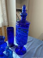 Tall footed apothecary jar, cylindrical vase and surrounding pieces