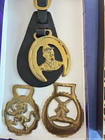 Single leather drop with portrait bust in horseshoe and two loose brasses—windmill and heraldic lion