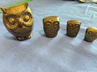 Front view of four brass owls lined by size