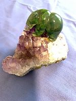 Large green stone animal figurine on amethyst geode cluster