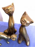 Three brass cat figurines on table