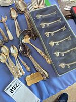 Group shot of flatware pieces, boxed fish-shaped forks, brass tag visible