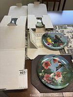 Four bird plates with boxes and certificates on table