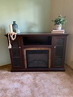 Front view of electric fireplace media console with decorative items on top