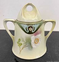 Front view of sugar bowl showing floral motif, two handles, and lid