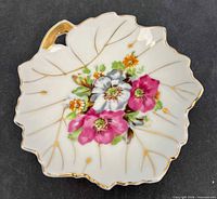 Front view of porcelain leaf dish showing floral motif and gold trim