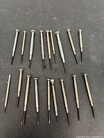 Full set of nineteen miniature screwdrivers laid out on dark surface