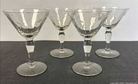 Four etched crystal stem glasses on black background