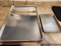 Large and small aluminum baking sheets side by side on counter