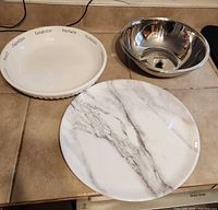 All three items grouped: ceramic pasta bowl, stainless bowl, marble print platter