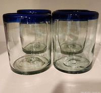 Four clear glass tumblers with blue rims front view