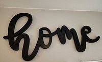 Black cursive home wall sign mounted on wall
