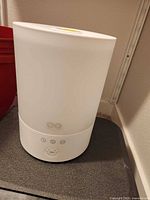 Front view of white cylindrical humidifier showing controls and logo