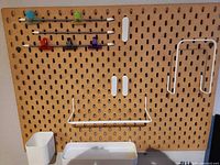 Tan pegboard with attached rails, clips, hooks, shelf, cup and tray