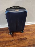 Front view of navy Ricardo hardside carry-on suitcase on four wheels