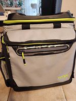 Front view showing Titan logo, front zip pocket, neon yellow zipper accents